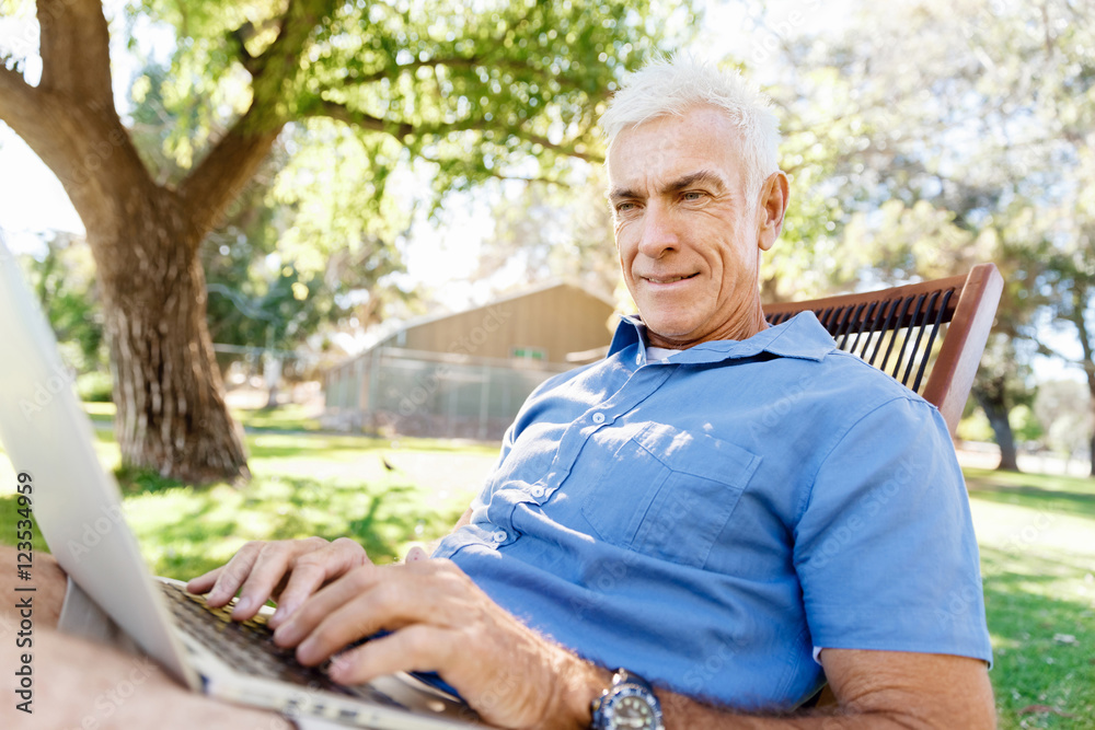 Senior man with notebook sitting in the park Senior man with notebook sitting in the park