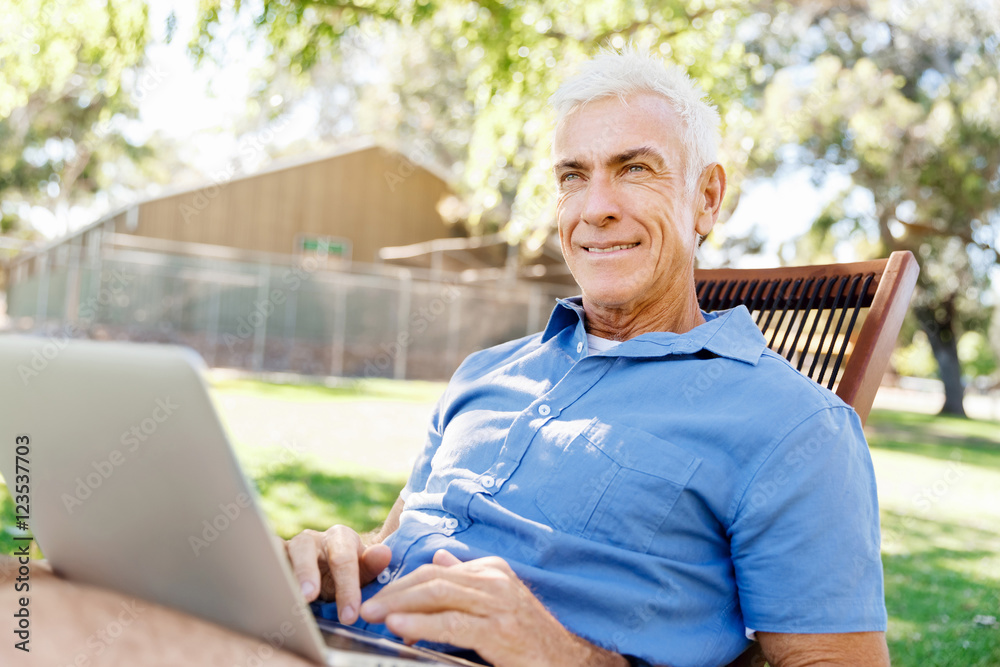 Senior man with notebook sitting in the park Senior man with notebook sitting in the park