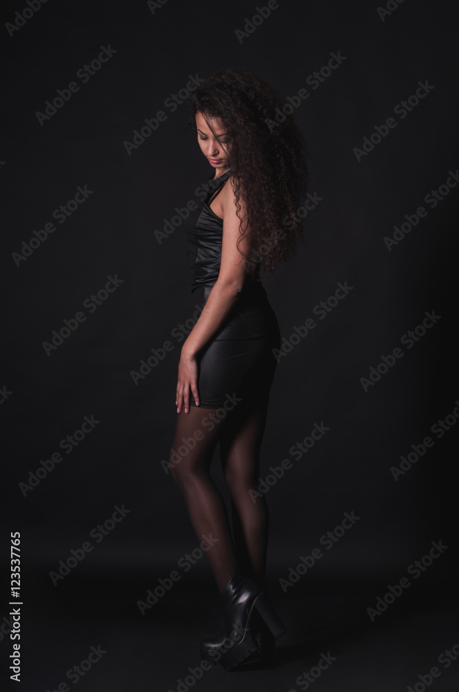 Pretty woman with long curly hair on dark background