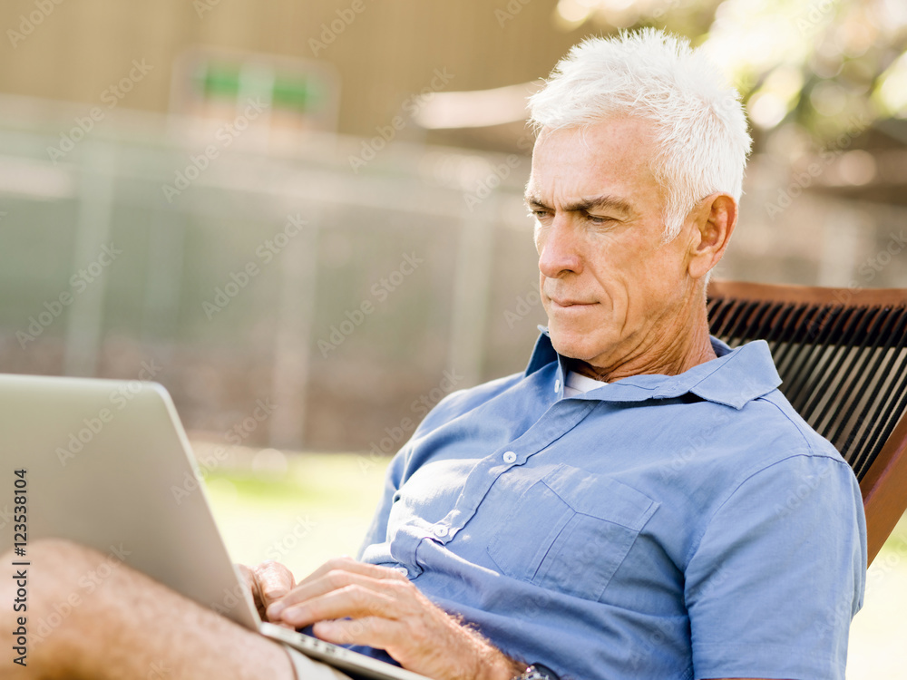Senior man with notebook sitting in the park Senior man with notebook sitting in the park