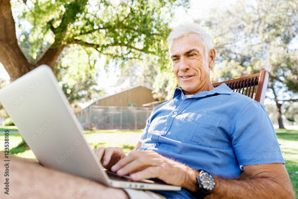Senior man with notebook sitting in the park Senior man with notebook sitting in the park