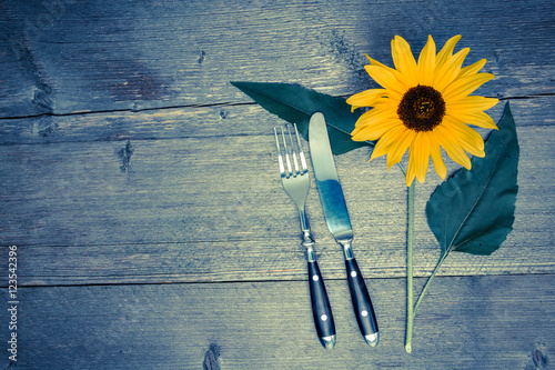 Besteck und Sonnenblume auf einem alten Tisch
