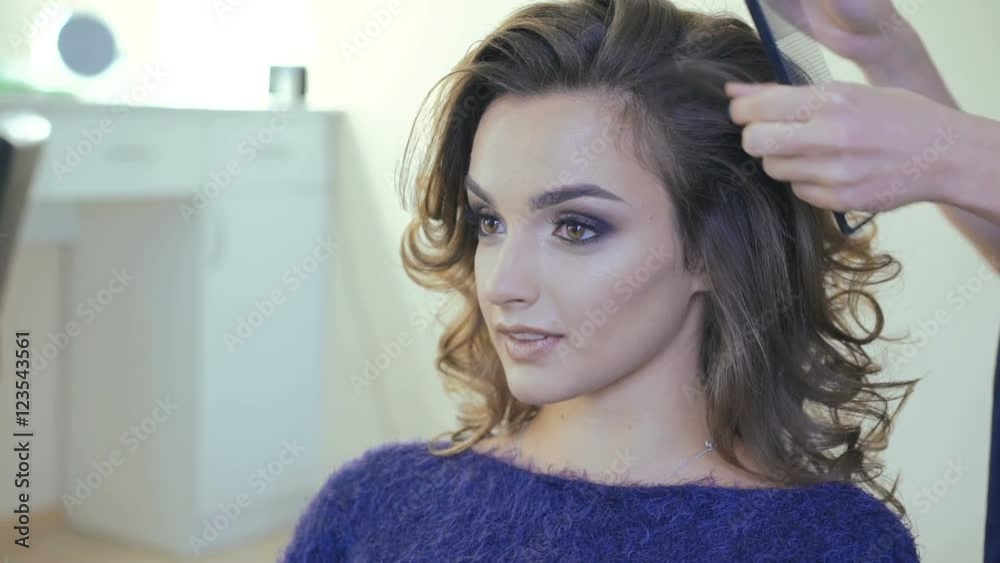 Hairdresser doing curles for smart woman in the studio Hairdresser doing curles for smart woman in the studio