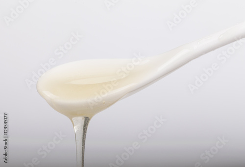Honey and white spoon on the white