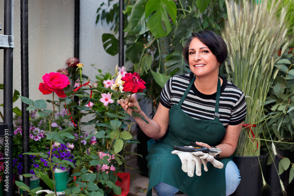 Glad mature woman florist smiling among plants
