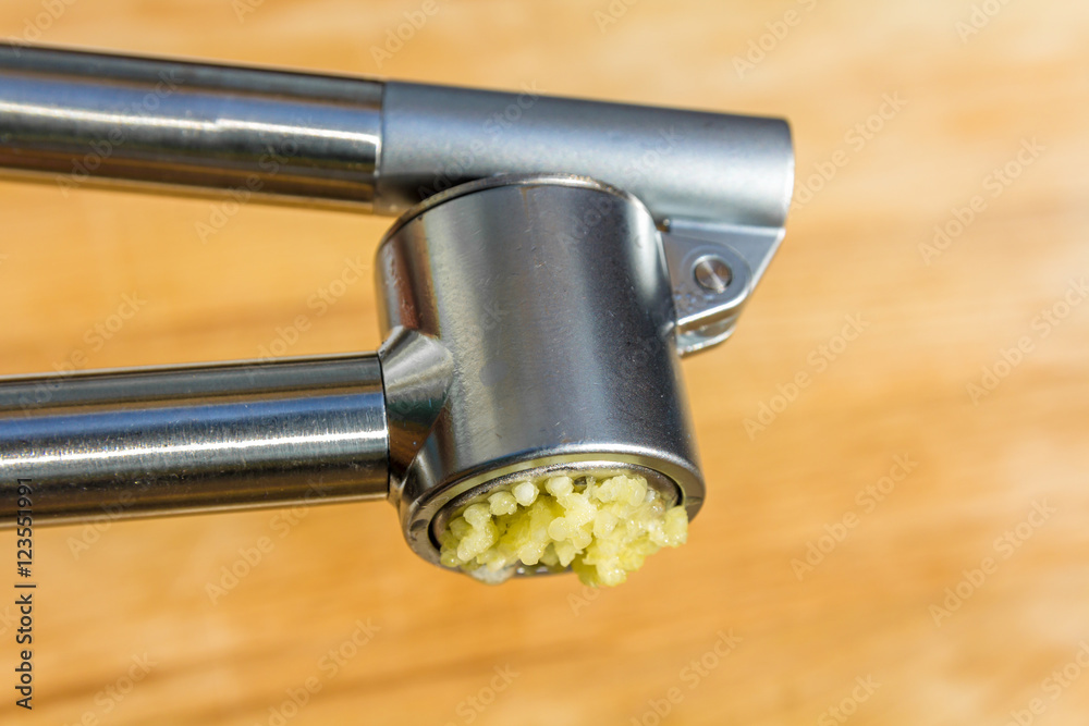 clove of garlic being crushed in garlic pres clove of garlic being crushed in garlic pres