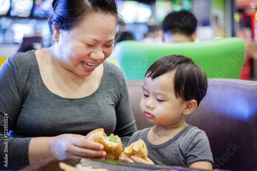Mother and little boy enjoy eat hamburger