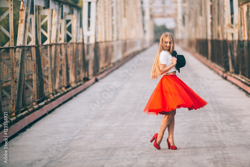 Wallpaper Mural stylish portrait of a beautiful young woman on the bridge in a red skirt and bla