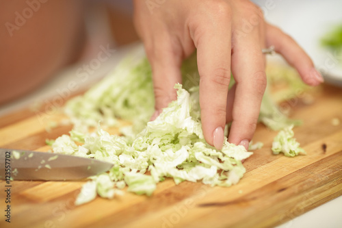pregnant woman cuts cabbage on wooden Board, close-up