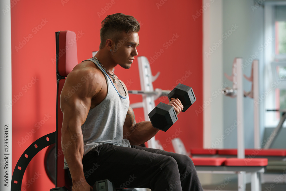 Handsome man training with dumbbells in gym Handsome man training with dumbbells in gym