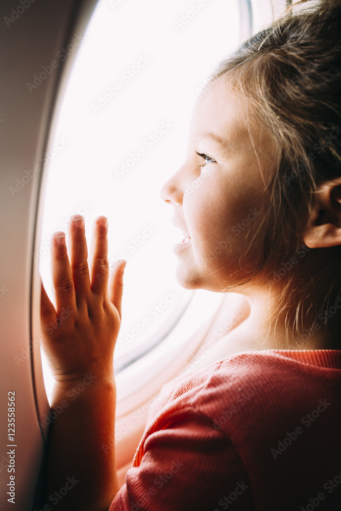 Curious girl looking through airplane window Curious girl looking through airplane window