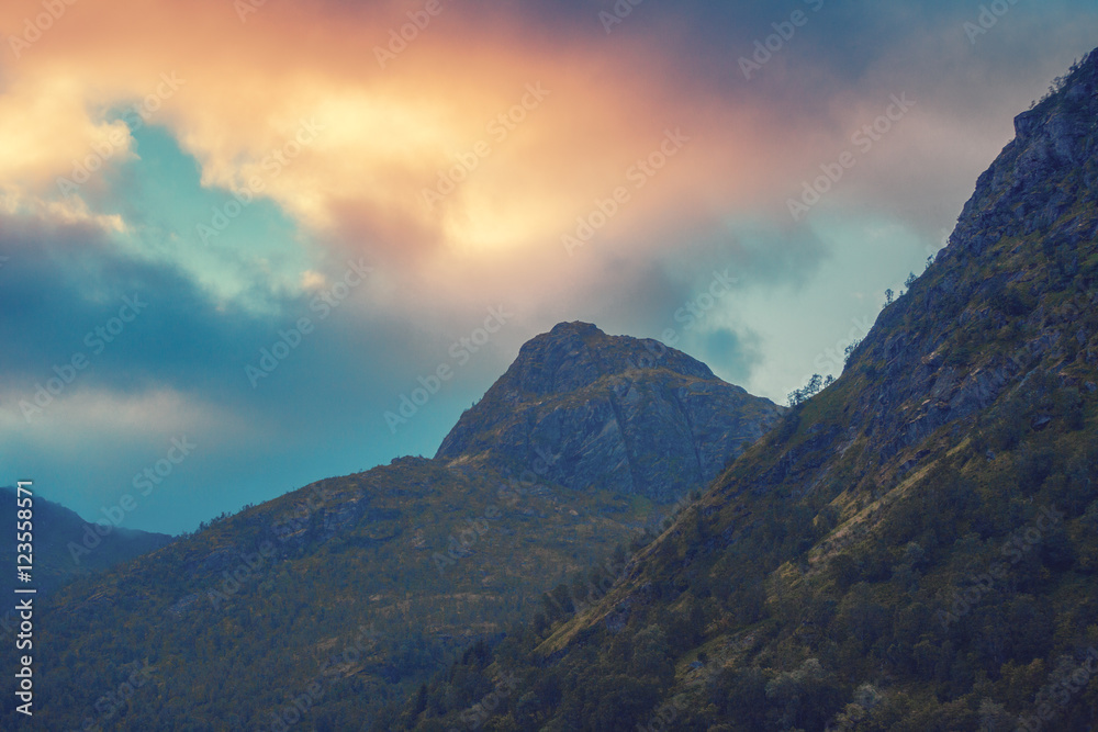 Sunset over mountains. Evening cloudy sky over mountains peaks