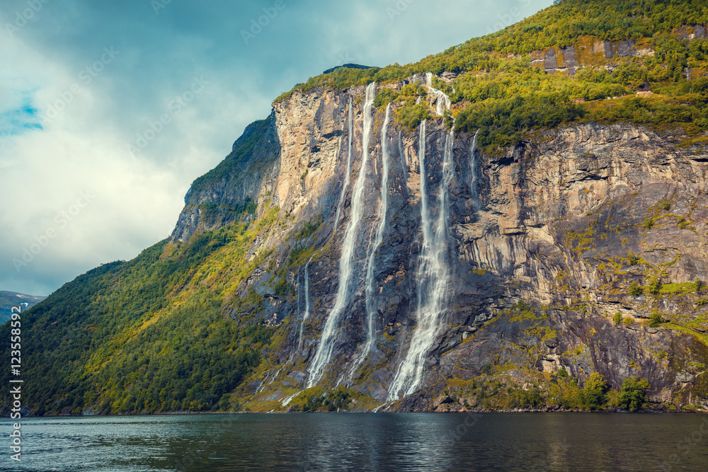 Obraz premium Mountain landscape with cloudy sky. Beautiful nature Norway.Geiranger fjord. Seven Sisters Waterfall