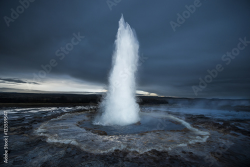 Strokkur geyser erupting against cloudscape