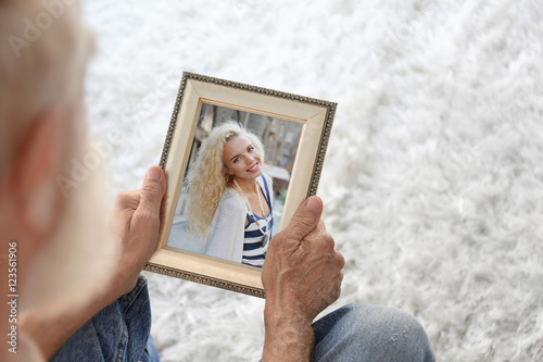 Elderly man holding photo f...