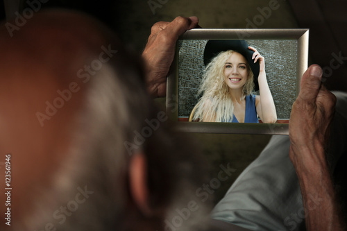 Elderly man holding photo f...
