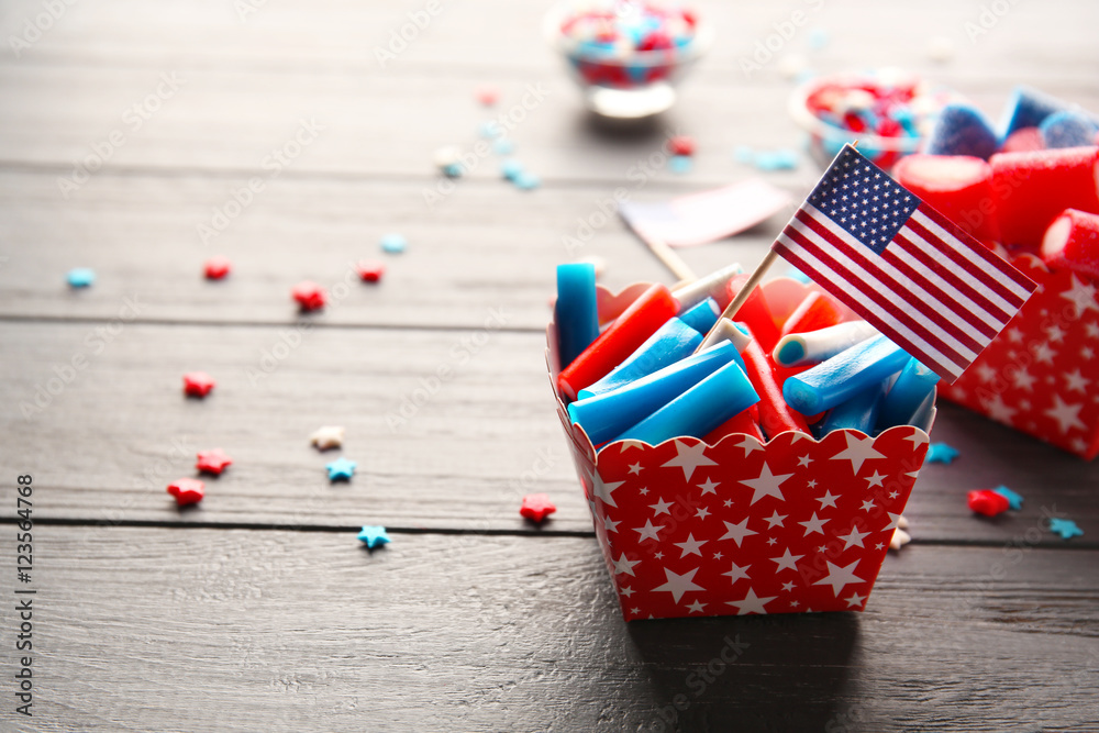Obraz premium Delicious candies with USA flag in paper box on dark wooden background