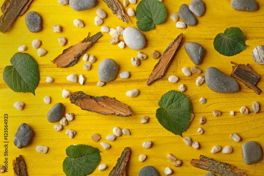 Scattering of pebbles, leaves and pieces of bark on yellow wooden background Scattering of pebbles, leaves and pieces of bark on yellow wooden background