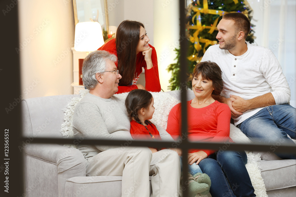Happy family in living room decorated for Christmas, view from window Happy family in living room decorated for Christmas, view from window