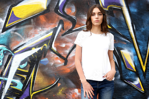 Young woman in blank t-shirt against graffiti wall