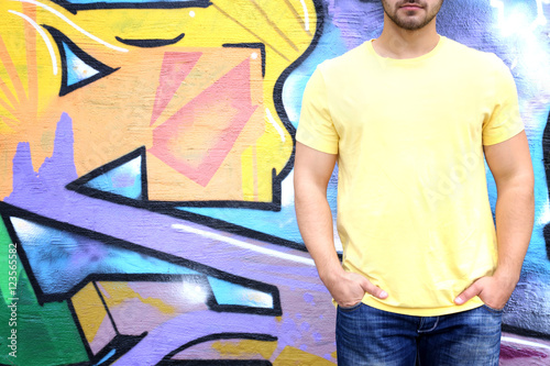 Young man in blank t-shirt against graffiti wall, closeup