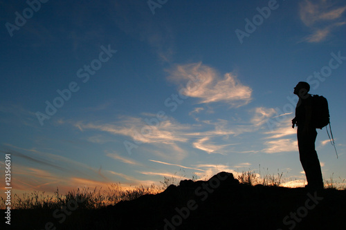 Silhouette of Backpacker Standing on Hill looking at Night Sky after Sunset