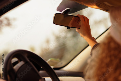 Canvas-taulu the girl in the car adjusts the rear view mirror