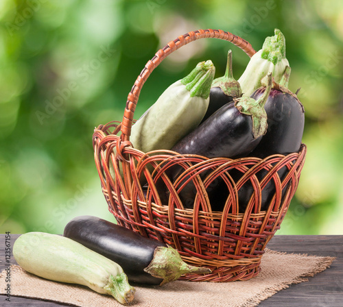 zucchini and eggplant in a wicker basket on  wooden table with  blurred background