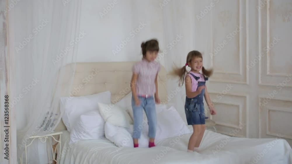 two little girls playing and jumping on the bed two little girls playing and jumping on the bed