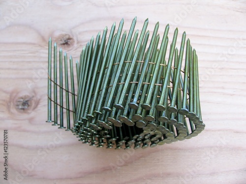 Принти на полотні Coil nails in roll for nailer guns on plywood background