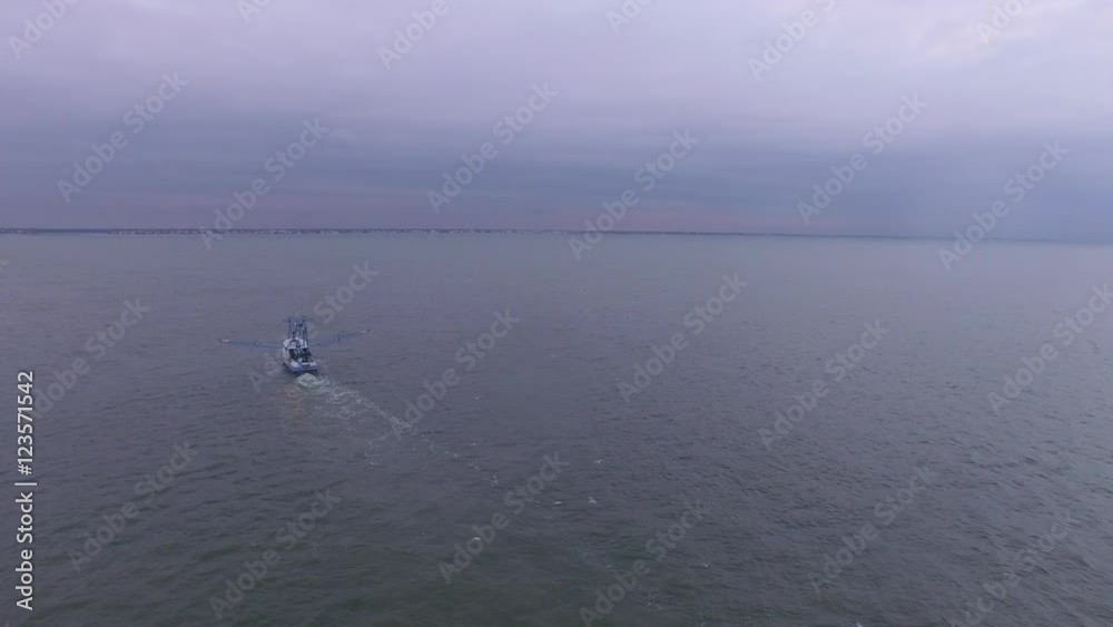 A shrimp boat trawls in open water in the Atlantic ocean, dragging its nets while seagulls fly around. A shrimp boat trawls in open water in the Atlantic ocean, dragging its nets while seagulls fly around.