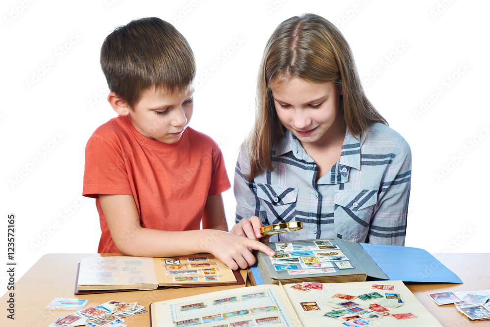 Teen girl and little boy with magnifier looking his stamp collec Teen girl and little boy with magnifier looking his stamp collec