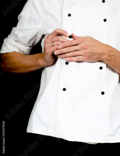 Professional chef buttoning up a white chefs jacket towards blac
