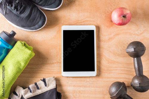Top view of Tablet with Sport stuff on wooden table background.