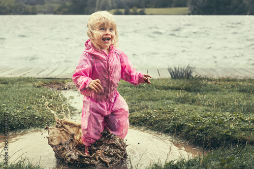 Happy toddler splashing in muddy puddle with look of joy