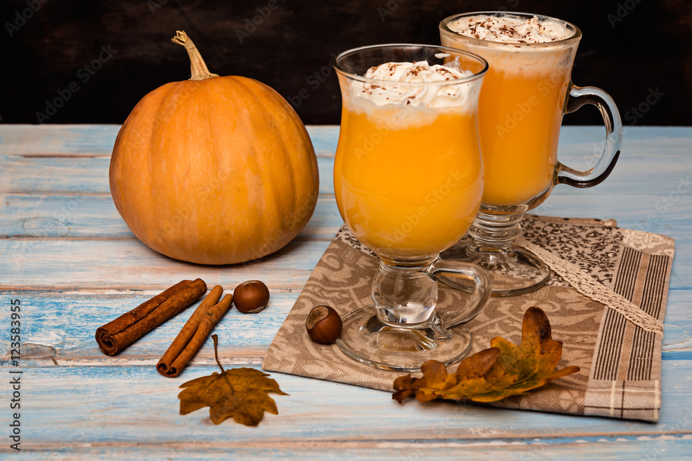 Pumpkin smoothie, spice latte with whipped  cream on the rustic wooden background.  selective focus