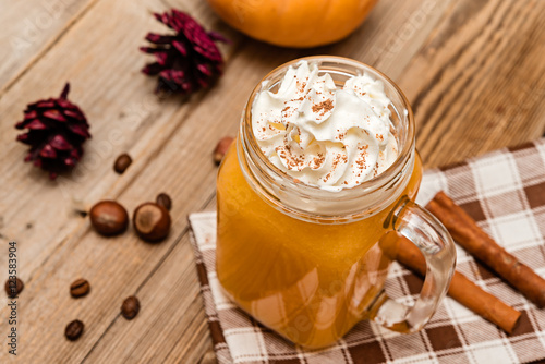 Pumpkin smoothie, spice latte with whipped  cream on the rustic wooden background.  selective focus