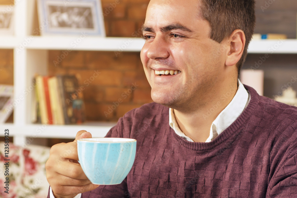 Young man holding a cup of coffee in hand and smiling. Young man holding a cup of coffee in hand and smiling.