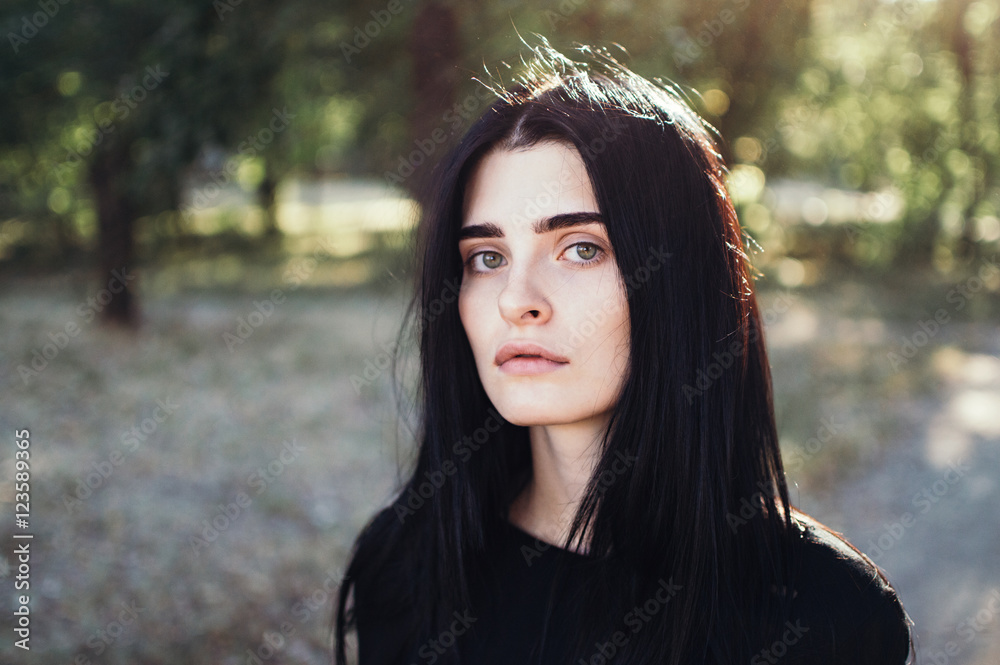 Outdoors portrait of beautiful young brunette woman looking at camera Outdoors portrait of beautiful young brunette woman looking at camera