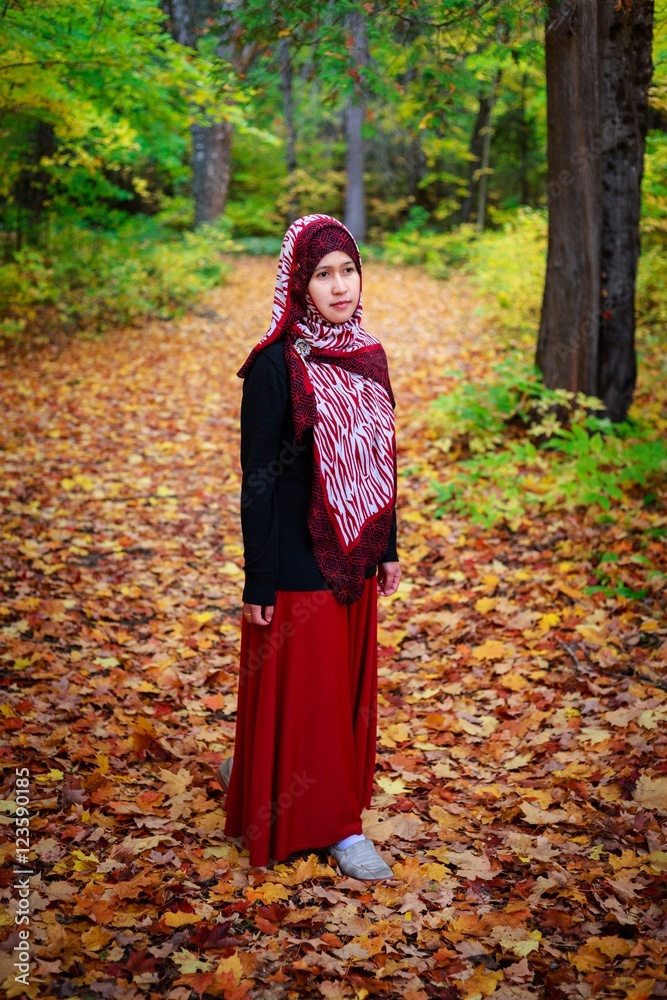Muslim woman in Canada during autumn with colorful maple leaf as background Muslim woman in Canada during autumn with colorful maple leaf as background