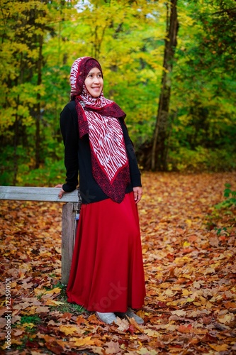 Muslim woman in Canada during autumn with colorful maple leaf as background 