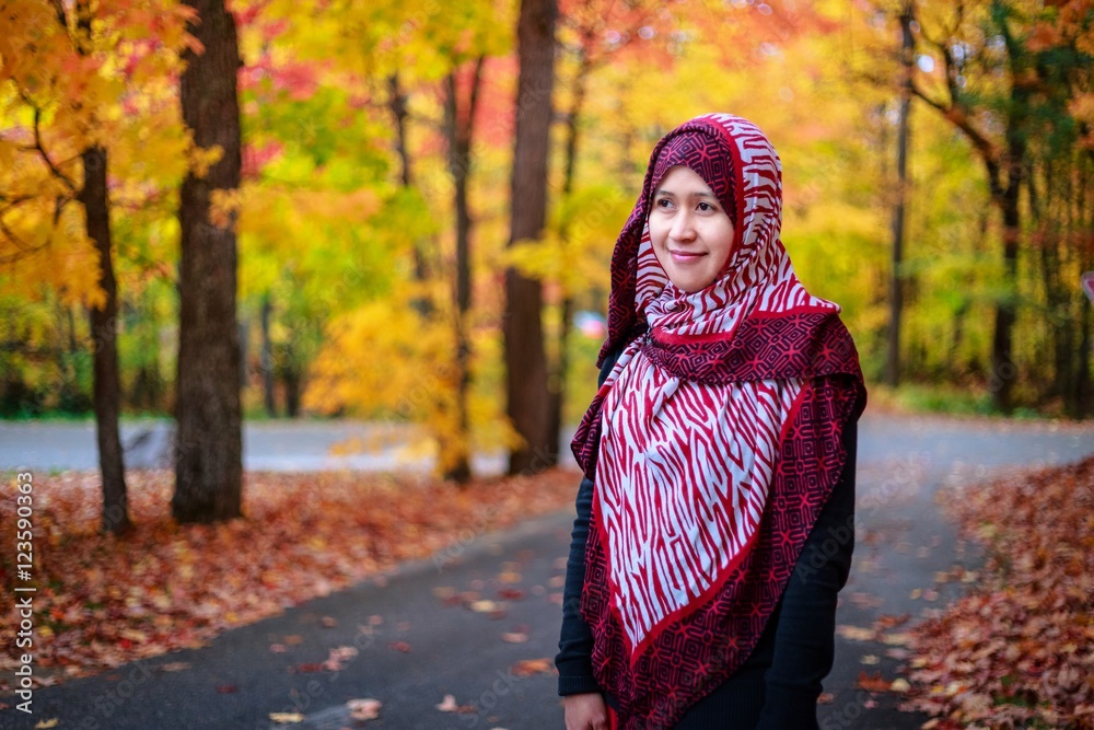Muslim woman in Canada during autumn with colorful maple leaf as background Muslim woman in Canada during autumn with colorful maple leaf as background