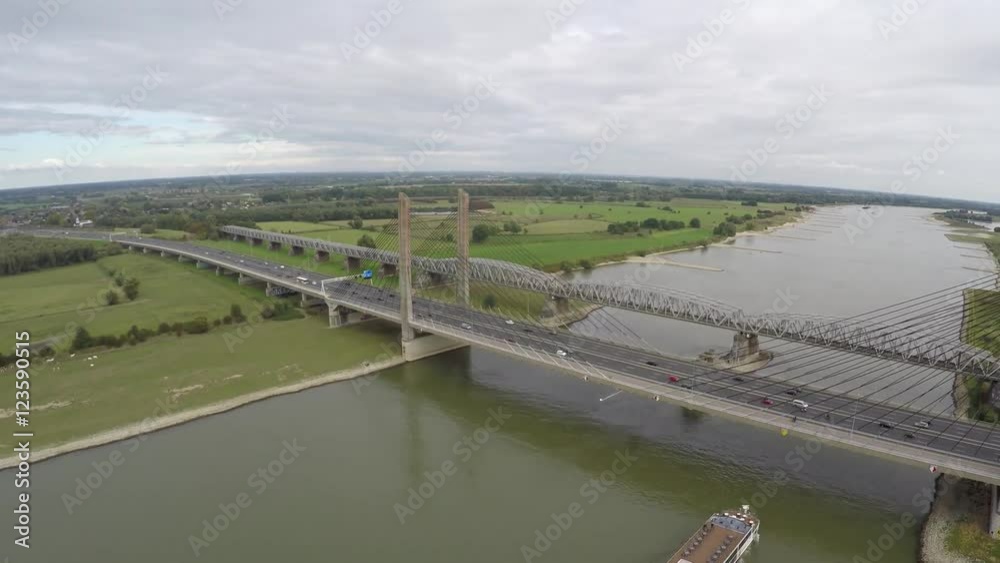 Aerial of briges with traffic moving over and barge transport ship moving underneath it on the cable-stayed bridge a highway is running over on smaller bridge a railroad over river steady flight 4k Aerial of briges with traffic moving over and barge transport ship moving underneath it on the cable-stayed bridge a highway is running over on smaller bridge a railroad over river steady flight 4k
