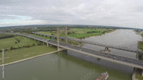 Aerial of briges with traffic moving over and barge transport ship moving underneath it on the cable-stayed bridge a highway is running over on smaller bridge a railroad over river steady flight 4k photo
