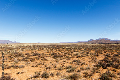 Barren field with mountains and blue sky