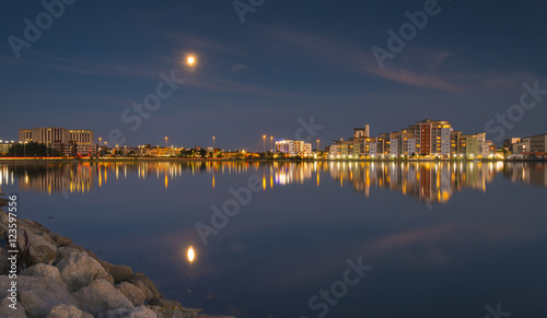 The moon and cityscape lights, reflect off harbour waters, poole
