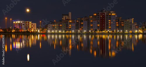 Fényképezés The moon and cityscape lights, reflect off harbour waters, poole
