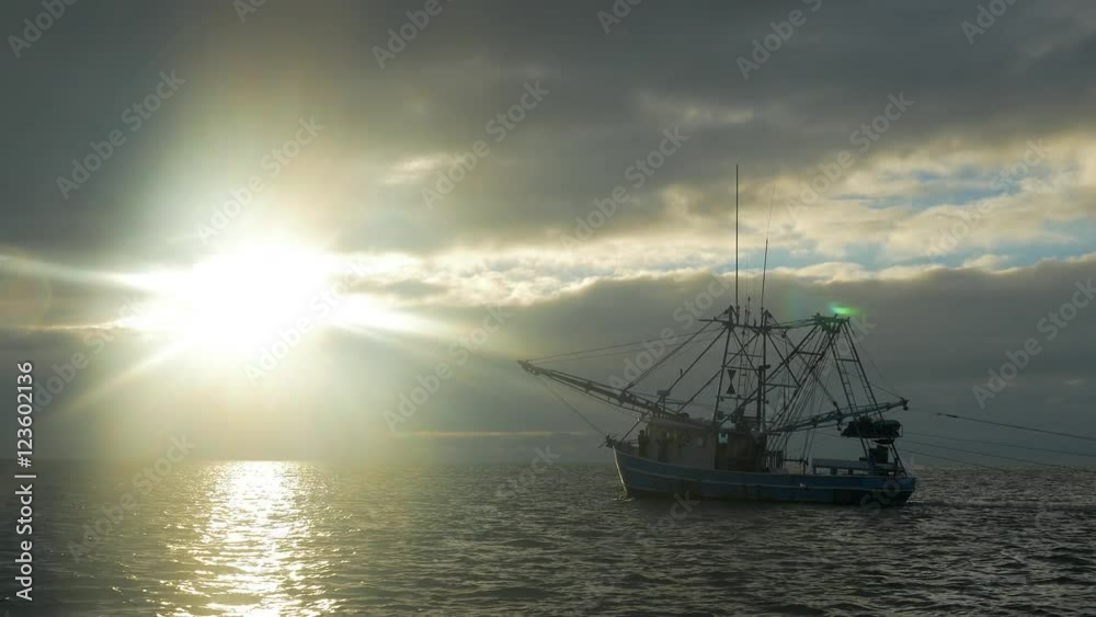 Shrimping trawler fishing just after sunrise with nets in the water. Shrimping trawler fishing just after sunrise with nets in the water.
