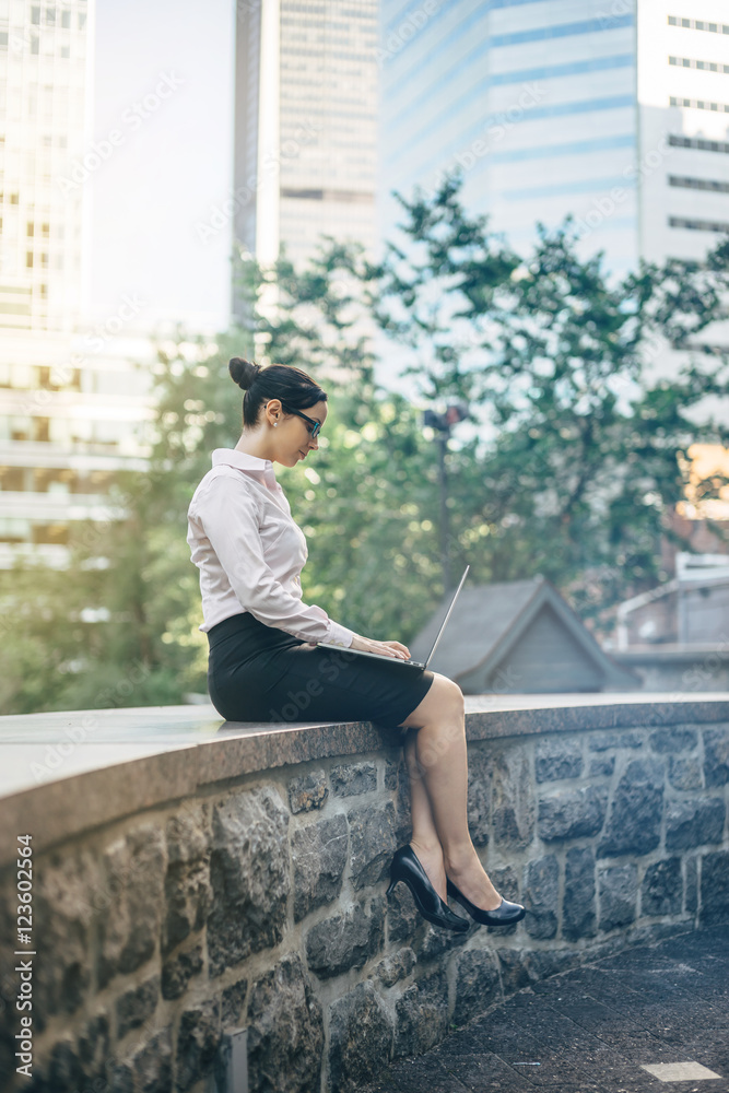 Attractive young businesswoman wearing white shirt working outdoors, Account manager working outdoors, Photo business woman wearing white shirt and working on laptop outdoors, blurred background