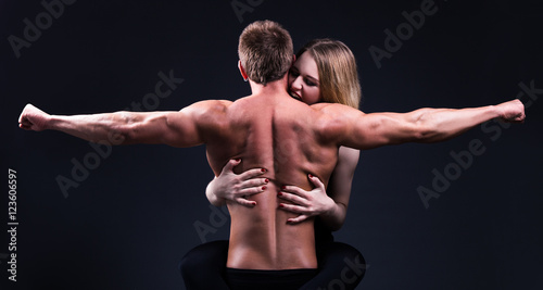 beautiful woman embracing and biting muscular man over grey © Di Studio